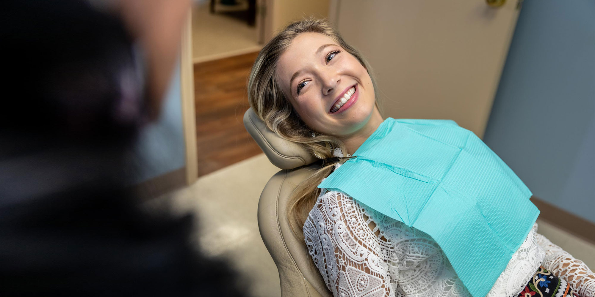 Young woman smiling in a dental chair after receiving general dentistry care