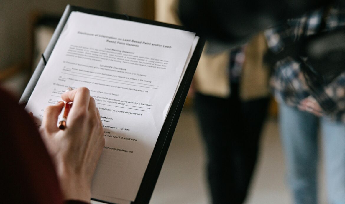 Patient hand filling out medical form on clipboard at a dental office
