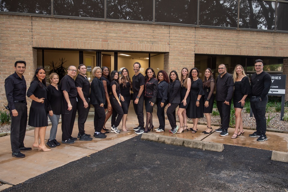 Dr. Friedberg & Associates dental team standing outside the Houston office, smiling in black uniforms