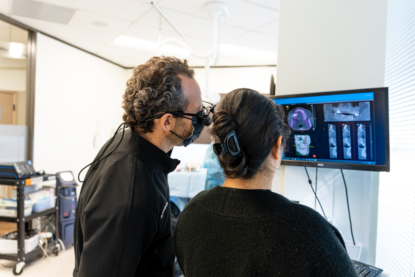 Dr. Friedberg reviewing dental imaging with a patient to explain when to see a periodontist for gum disease and bone loss