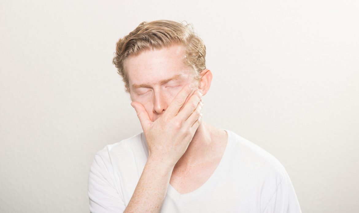 man holding face with swollen face tooth infection pain
