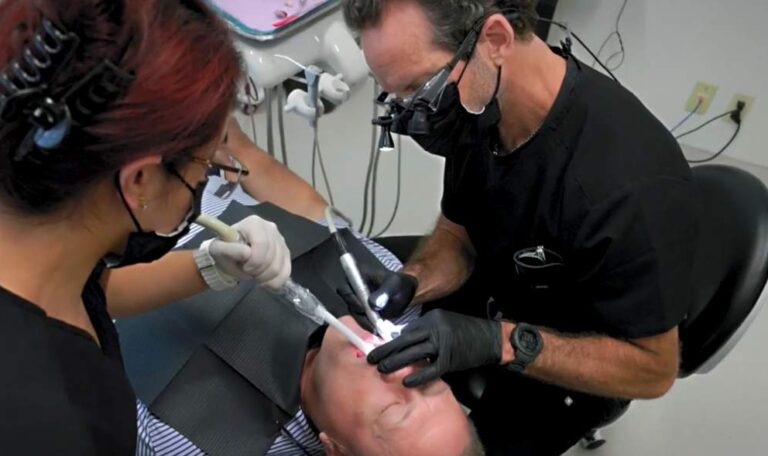 Dental implant specialist performing a dental implant procedure with surgical assistant