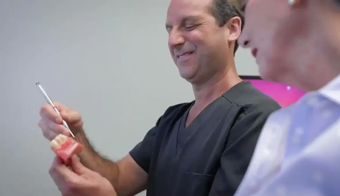 Dr. Friedberg using a dental model to explain gum anatomy to a patient
